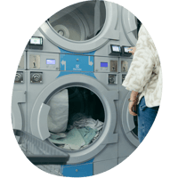 A person stands in front of several laundry machines.