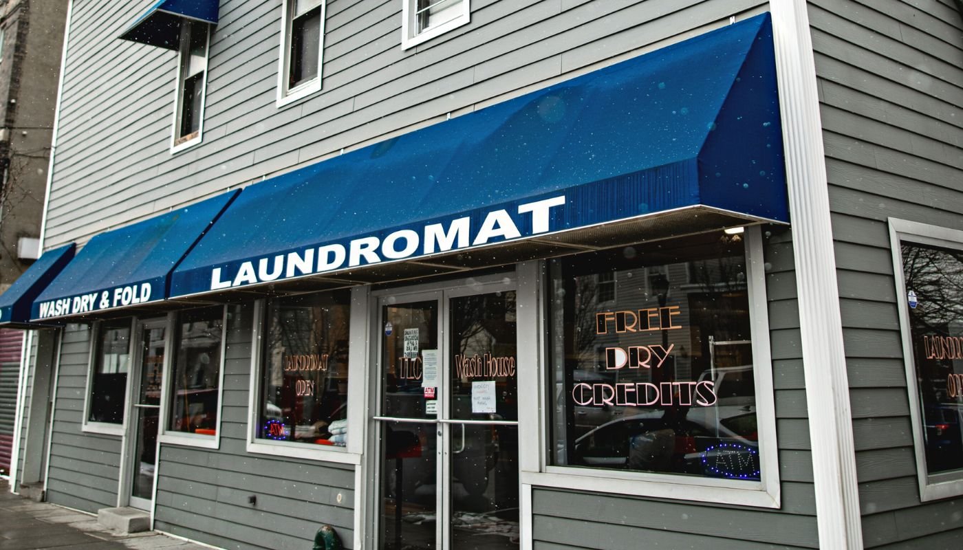 A picture of a laundromat with a blue awning