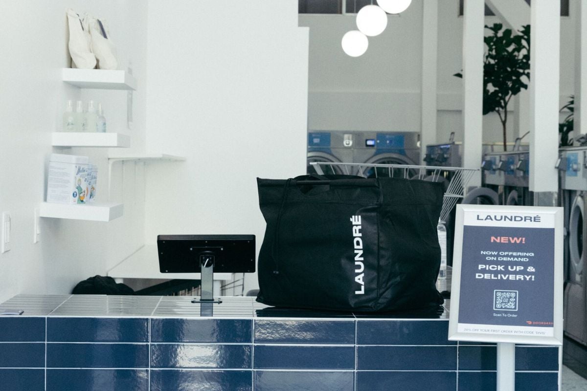 A counter in a laundromat with a Laundre bag and pickup and delivery sign