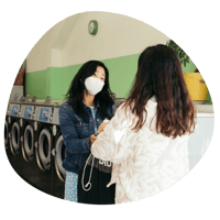 Two women conversing in the laundromat with masks on