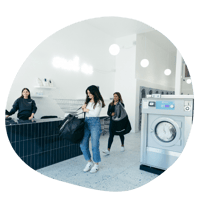 Two people use machines at a laundromat