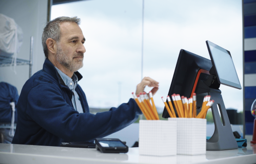 A picture of a laundromat owner at the front counter with a POS device